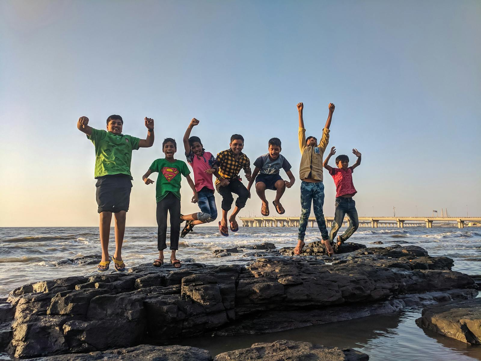Children Jumping from Black Stone on Seashore